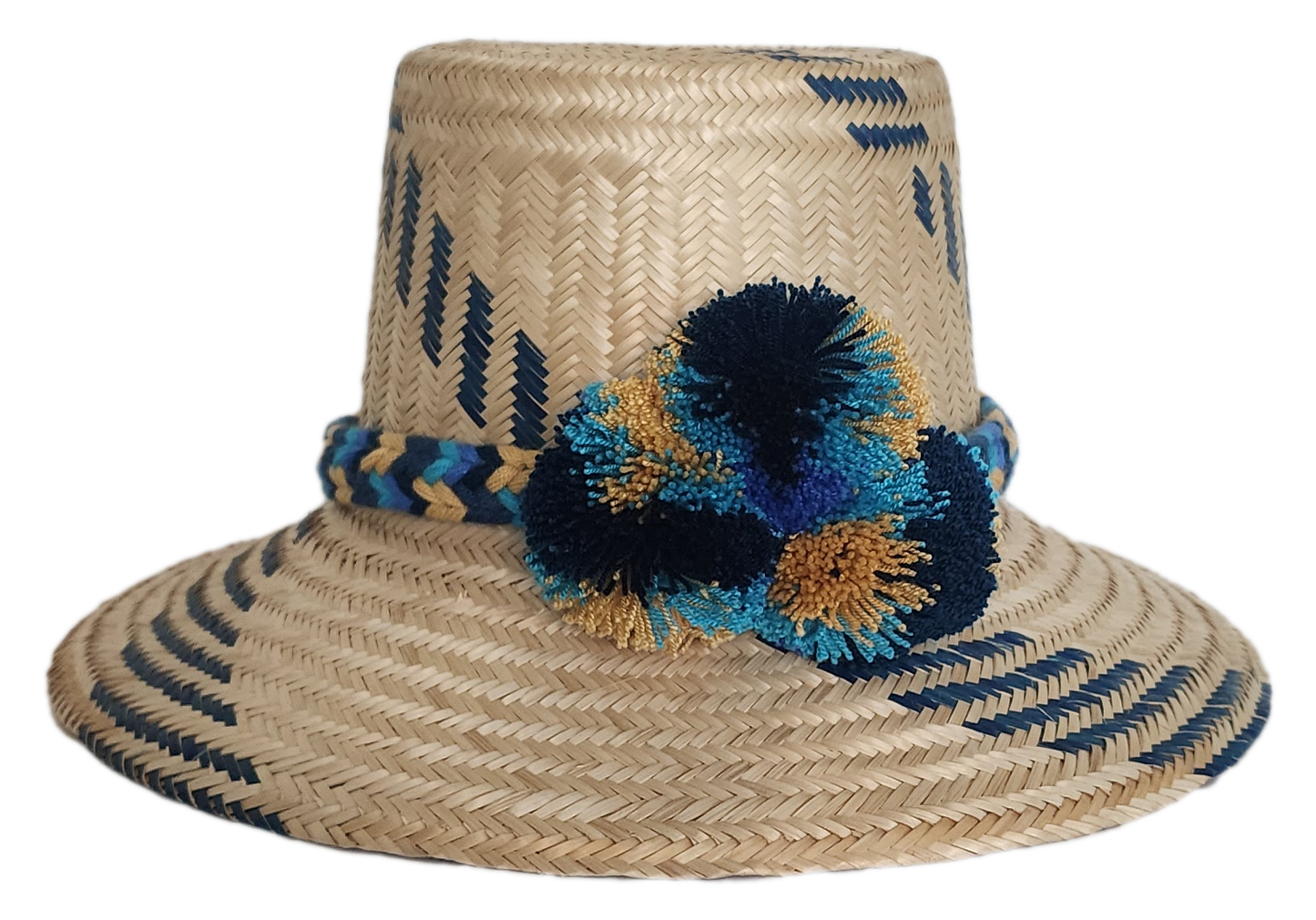 Boho Wayuu straw hat with navy blue and gold tribal-inspired patterns, a hand-braided band, and colorful pom-poms in blue, teal, and ochre — a bold, bohemian artisan accessory for summer style.