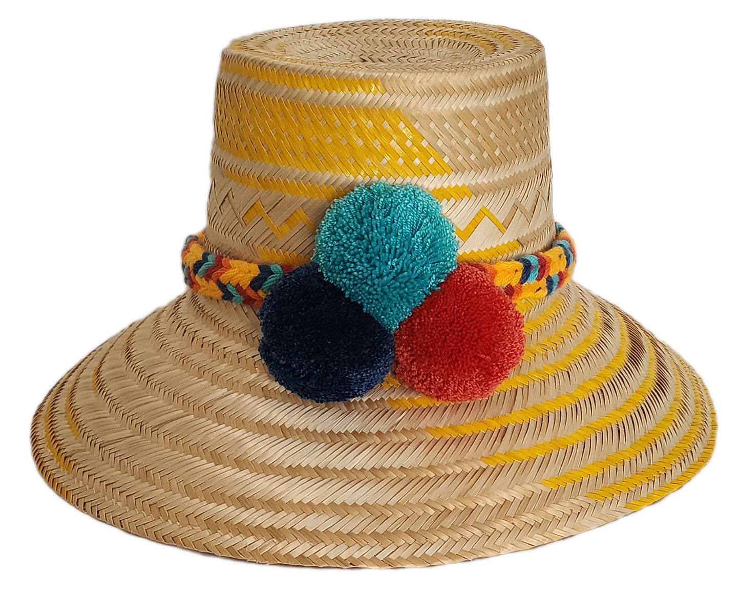 Boho Wayuu straw hat with yellow zigzag woven accents, a vibrant braided band, and colorful pom-poms in teal, red, and navy — a handcrafted bohemian accessory perfect for sunny days.