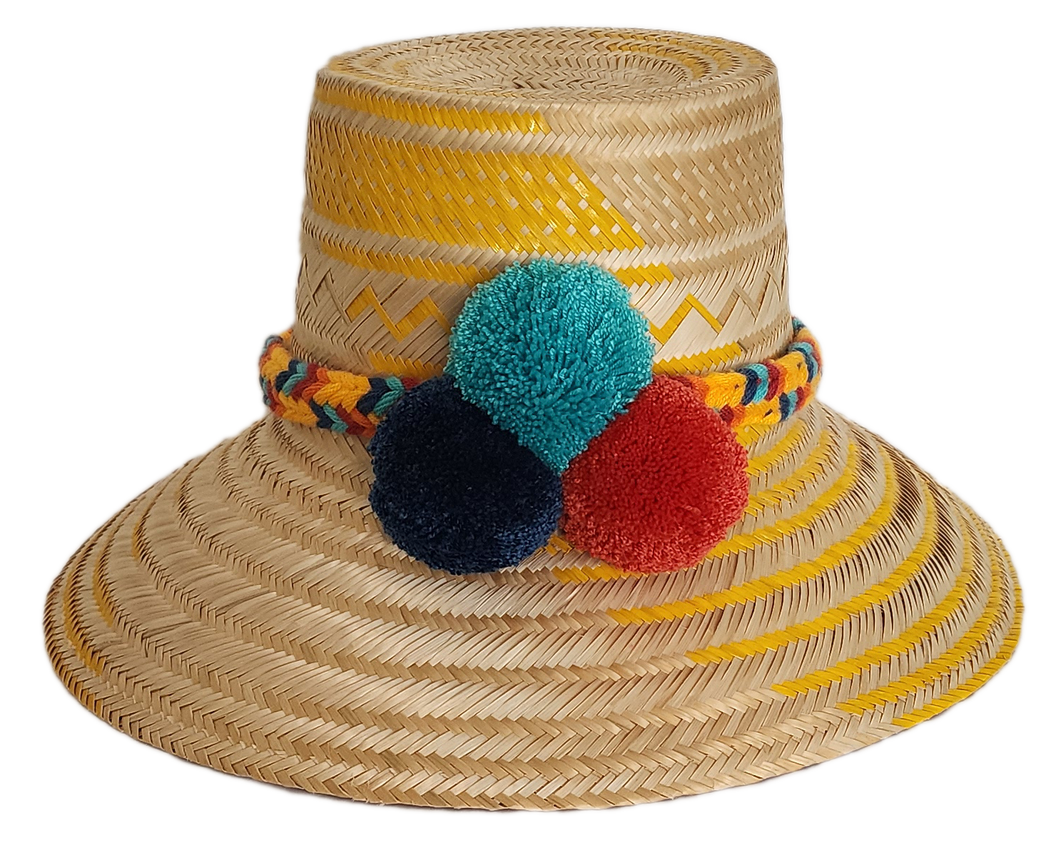 Boho Wayuu straw hat with yellow zigzag woven accents, a vibrant braided band, and colorful pom-poms in teal, red, and navy — a handcrafted bohemian accessory perfect for sunny days.