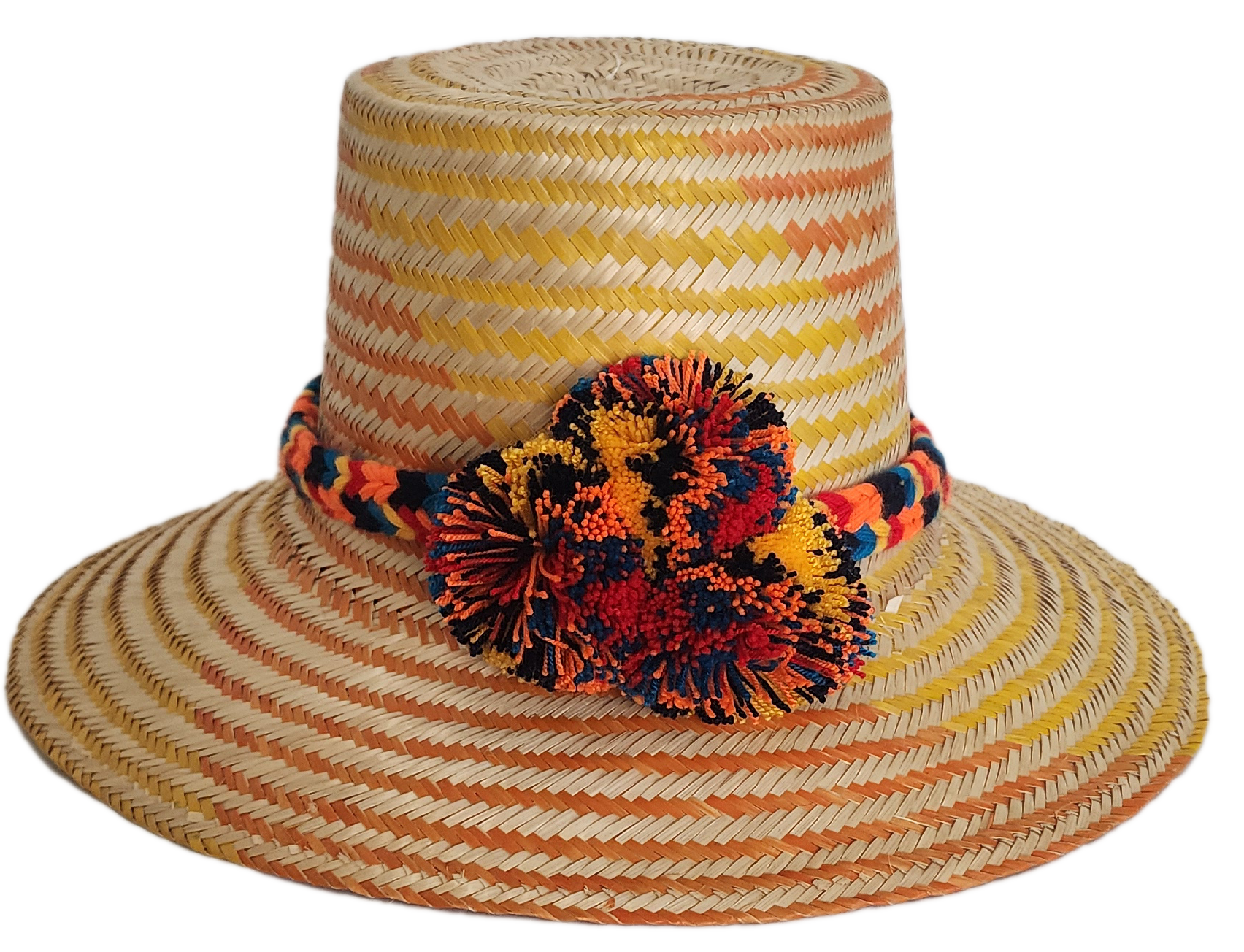 Boho Wayuu straw hat with warm orange and yellow woven patterns, a colorful braided band, and bold multicolor pom-poms — a vibrant, handcrafted bohemian accessory full of artisan detail.