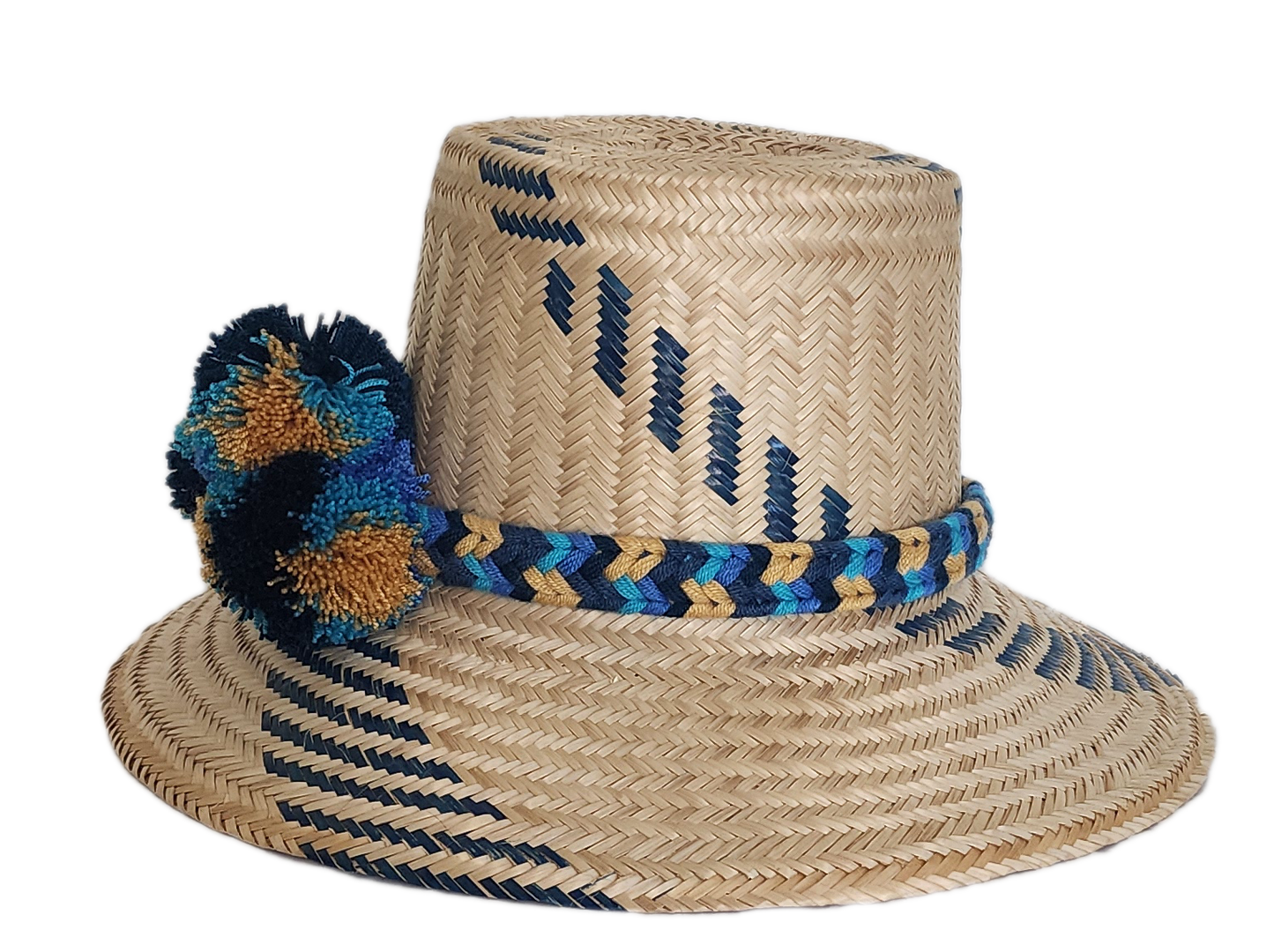 Boho Wayuu straw hat with navy blue and gold tribal-inspired patterns, a hand-braided band, and colorful pom-poms in blue, teal, and ochre — a bold, bohemian artisan accessory for summer style.