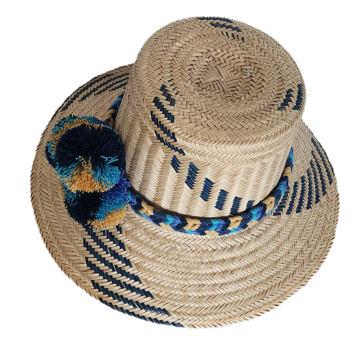Boho Wayuu straw hat with navy blue and gold tribal-inspired patterns, a hand-braided band, and colorful pom-poms in blue, teal, and ochre — a bold, bohemian artisan accessory for summer style.
