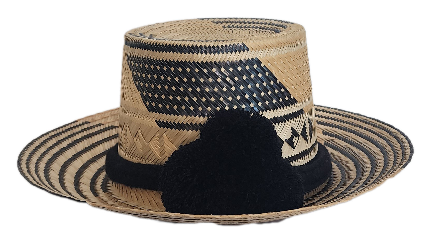 A stylish, handmade straw hat featuring intricate black and natural straw weaving patterns and a bold black pompom band.