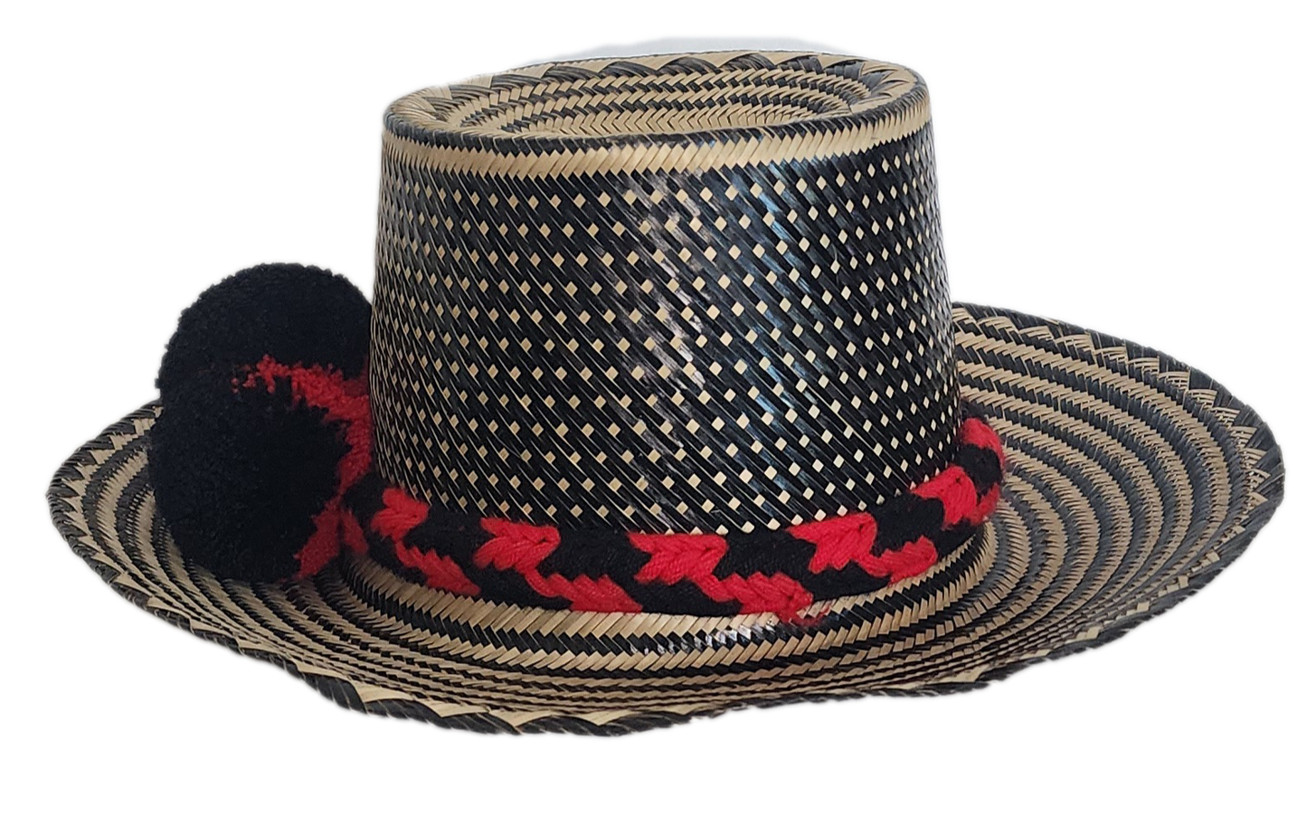 A colorful, handmade straw hat with intricate black and natural fiber weaving and a red and black pompom band.