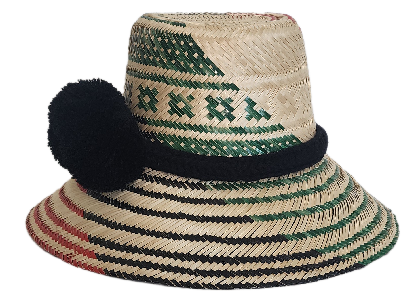 A vibrant, handmade straw hat featuring green and black geometric patterns on the crown and red and black stripes on the brim, accented by a bold black pompom band.