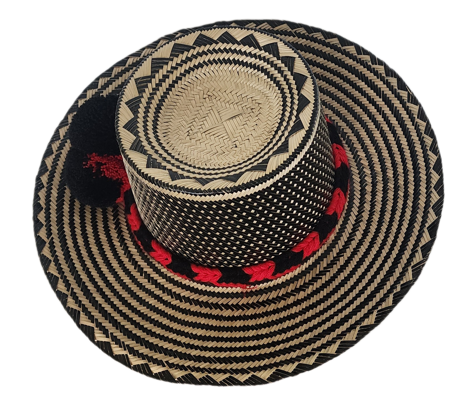 A colorful, handmade straw hat with intricate black and natural fiber weaving and a red and black pompom band.