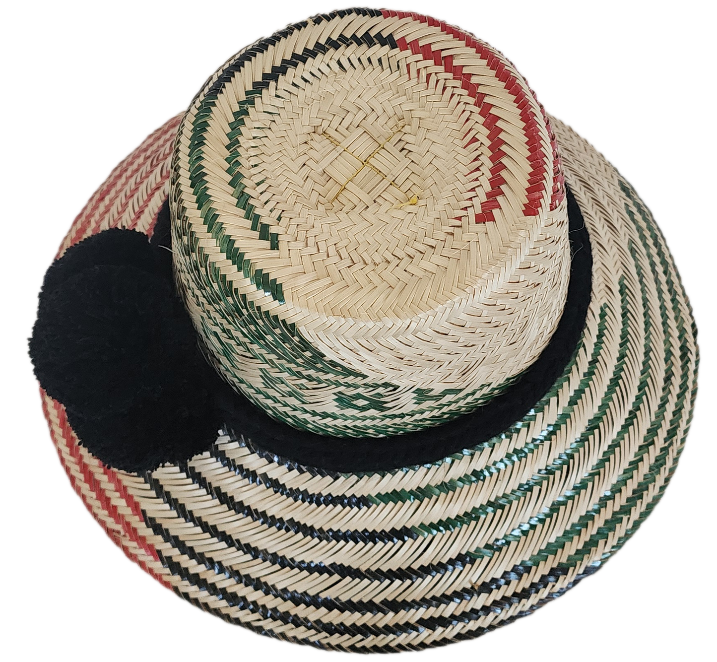 A vibrant, handmade straw hat featuring green and black geometric patterns on the crown and red and black stripes on the brim, accented by a bold black pompom band.