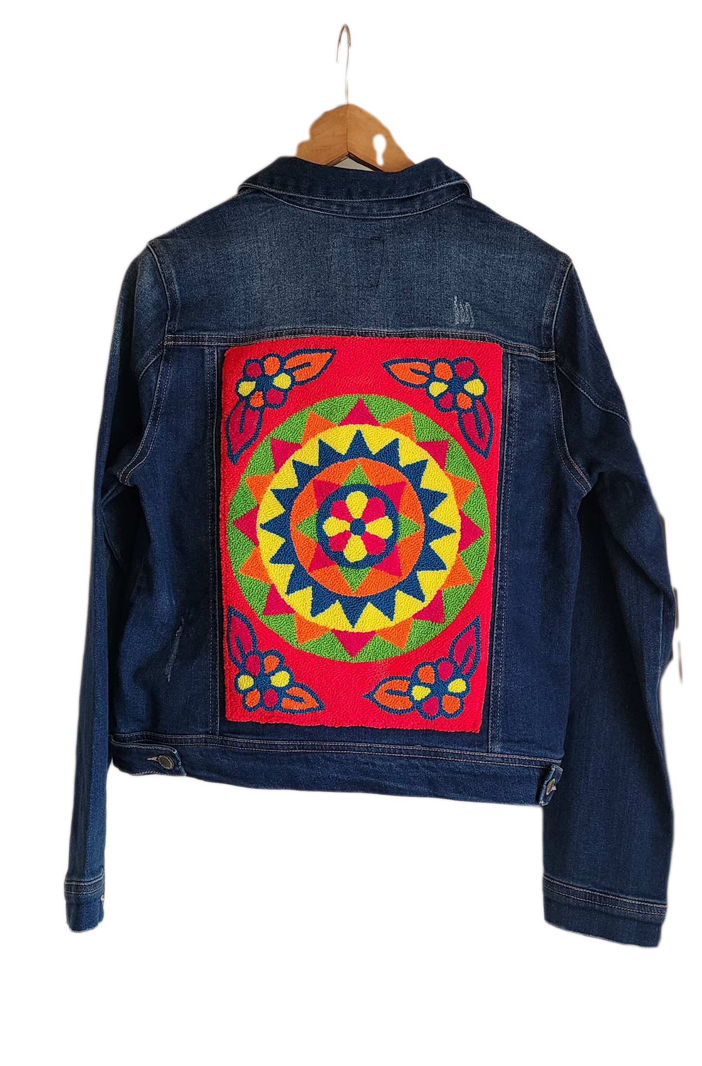 "Artisan-made denim jacket with vibrant, Wayuu-inspired punch needle embroidery on the back, showcasing unique craftsmanship.