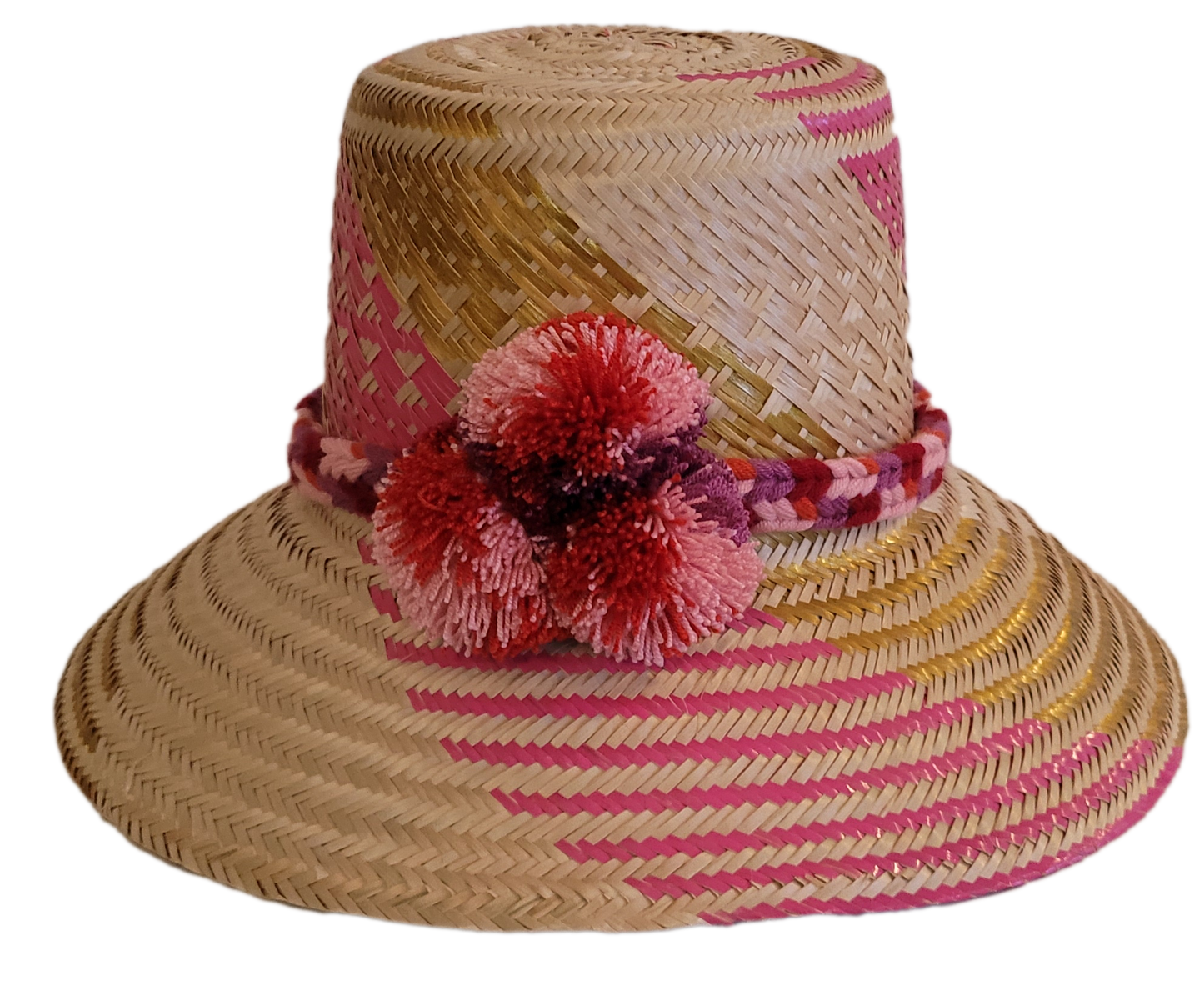 Handmade Wayuu straw hat with pink and golden patterns and red pompoms.