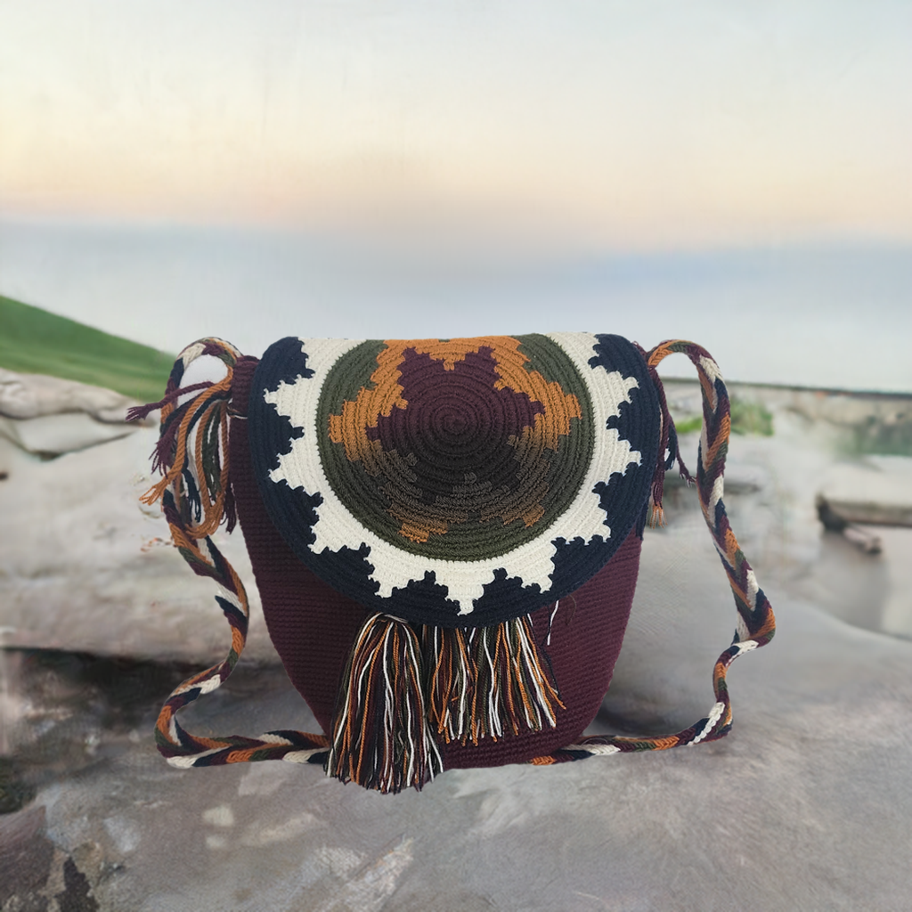 Handmade Wayuu crochet flap bag in rich earth tones with mustard, olive, and ivory sunburst design — artisan boho-chic accessory with fringe.