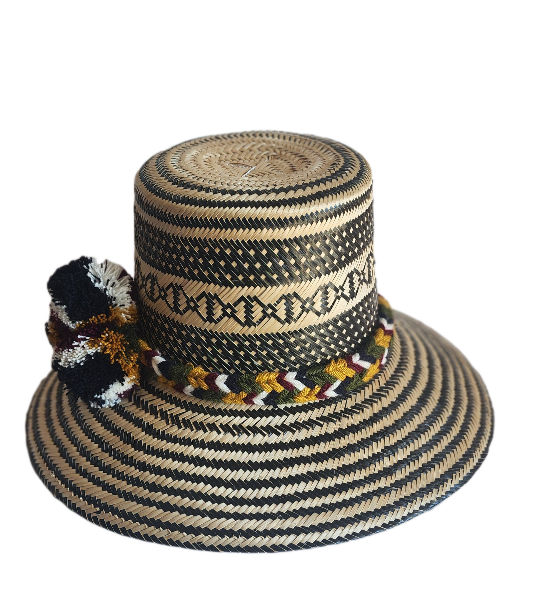 "Colorful handmade Wayuu hat crafted from Iraca palm with decorative pompoms, symbolizing wealth in Wayuu culture."