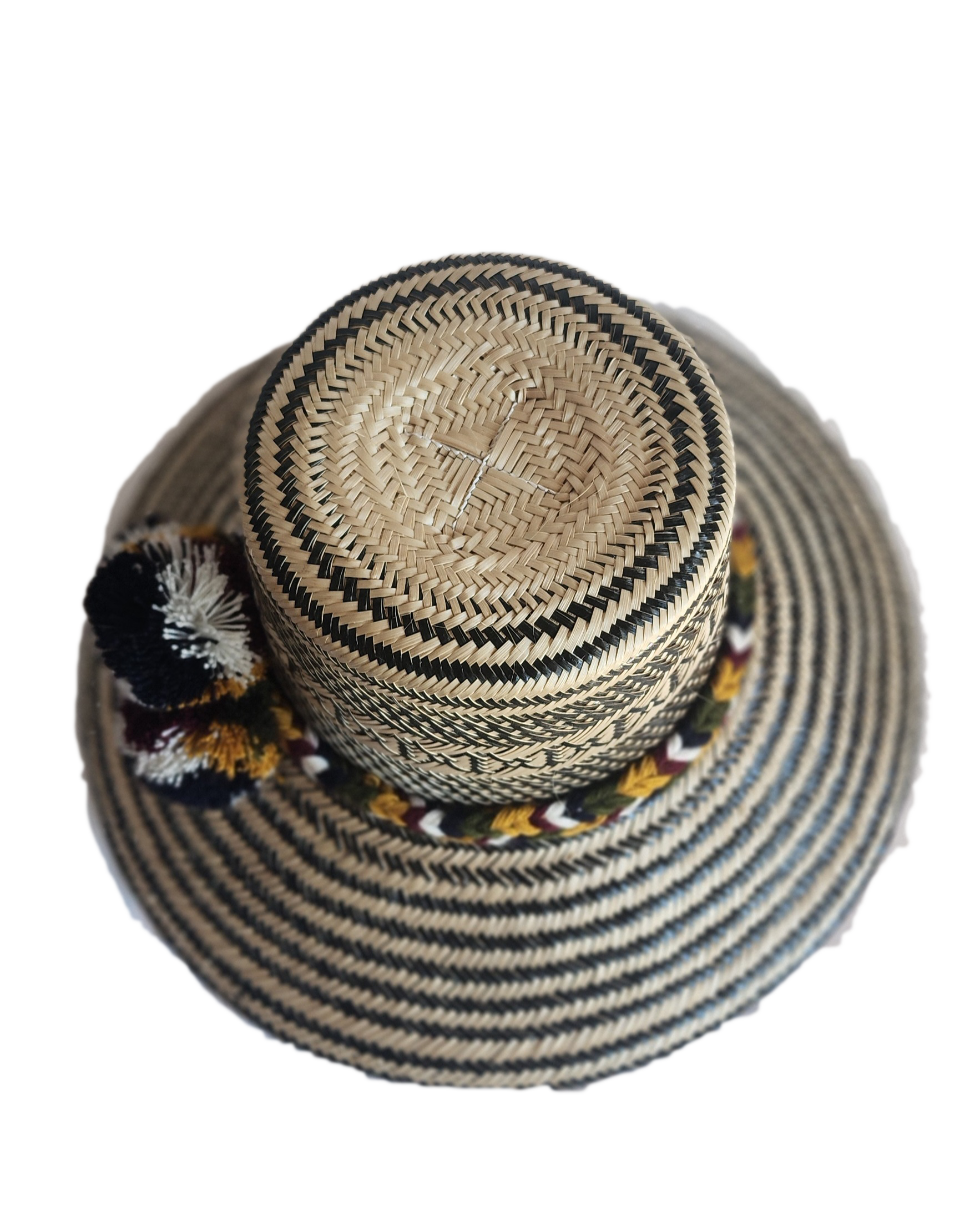 "Colorful handmade Wayuu hat crafted from Iraca palm with decorative pompoms, symbolizing wealth in Wayuu culture."