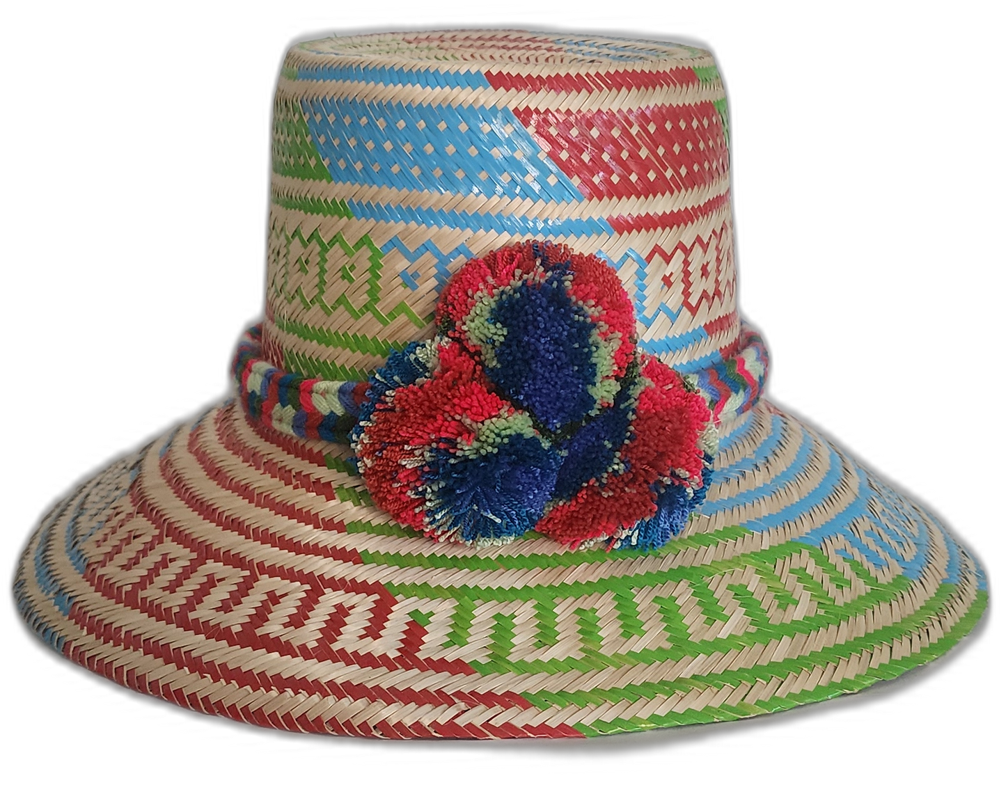 Handmade Wayuu boho straw hat with vibrant red, blue, and green woven patterns and bold pompom accents.