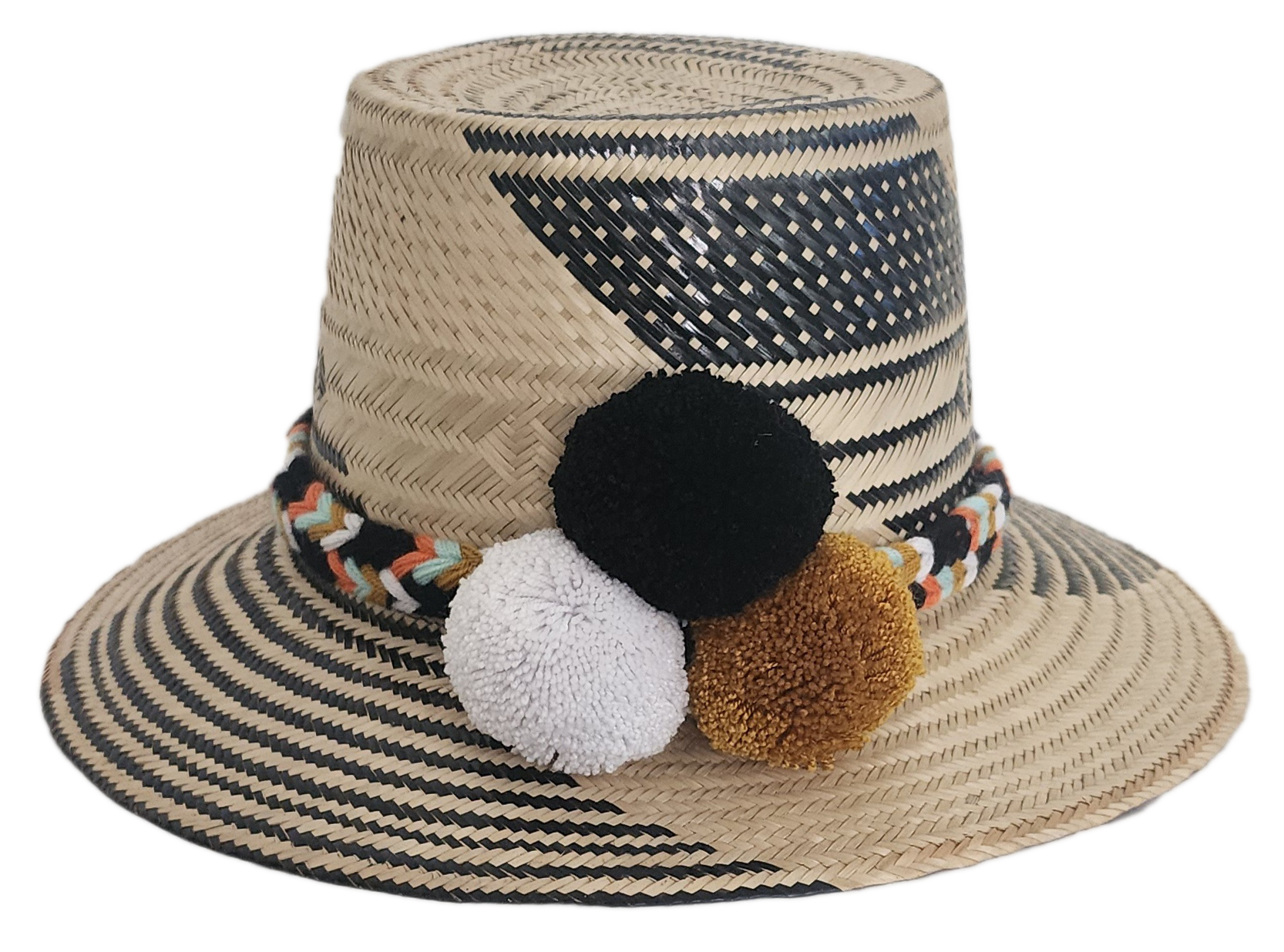 Handwoven Wayuu straw hat with bold black diagonal weave, a colorful braided band, and black, white, and mustard pom-poms. A refined boho fashion piece.