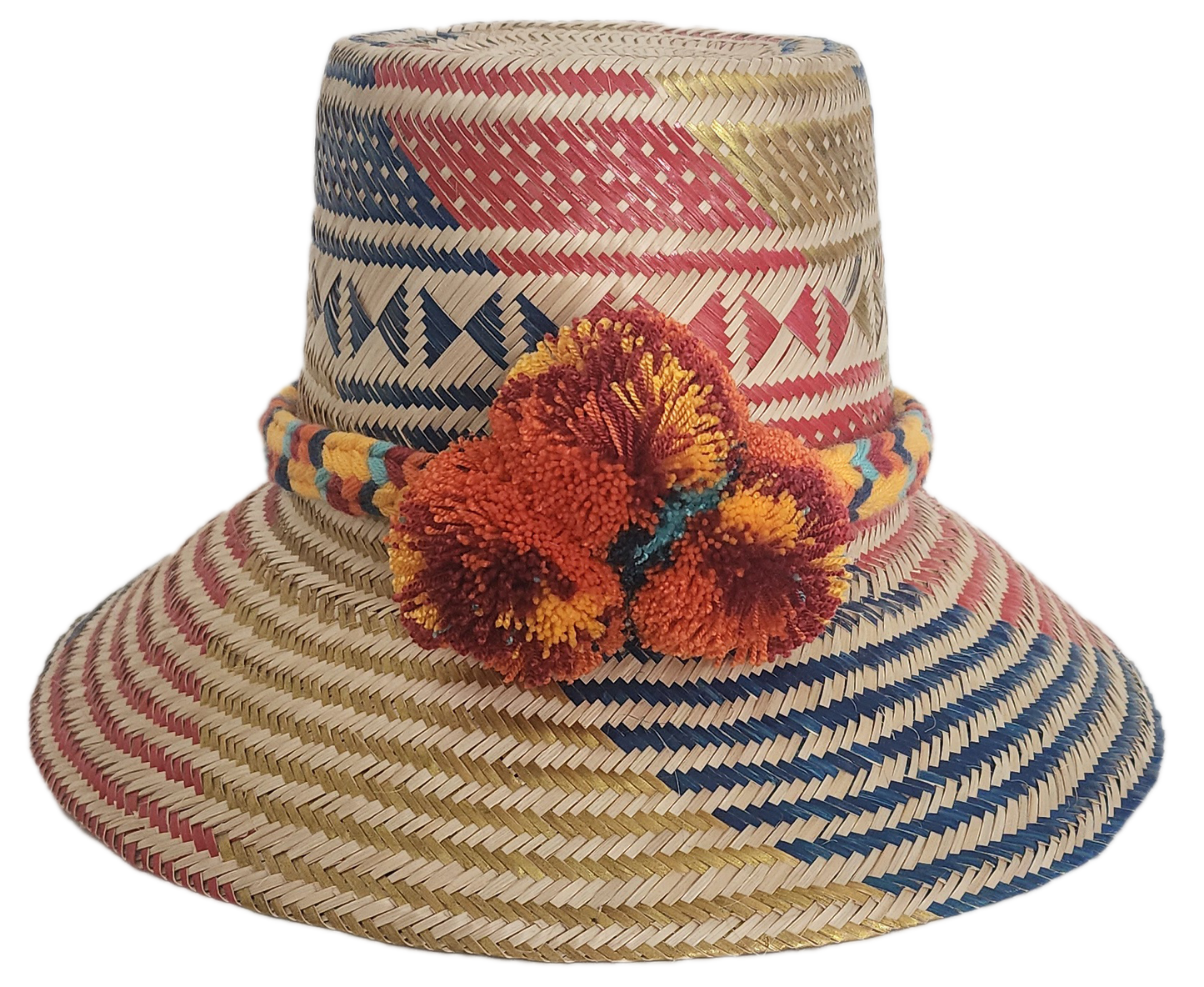 Handwoven Wayuu straw hat featuring red, navy, and golden tribal patterns, accented with a colorful braided band and vivid orange and maroon pom-poms.