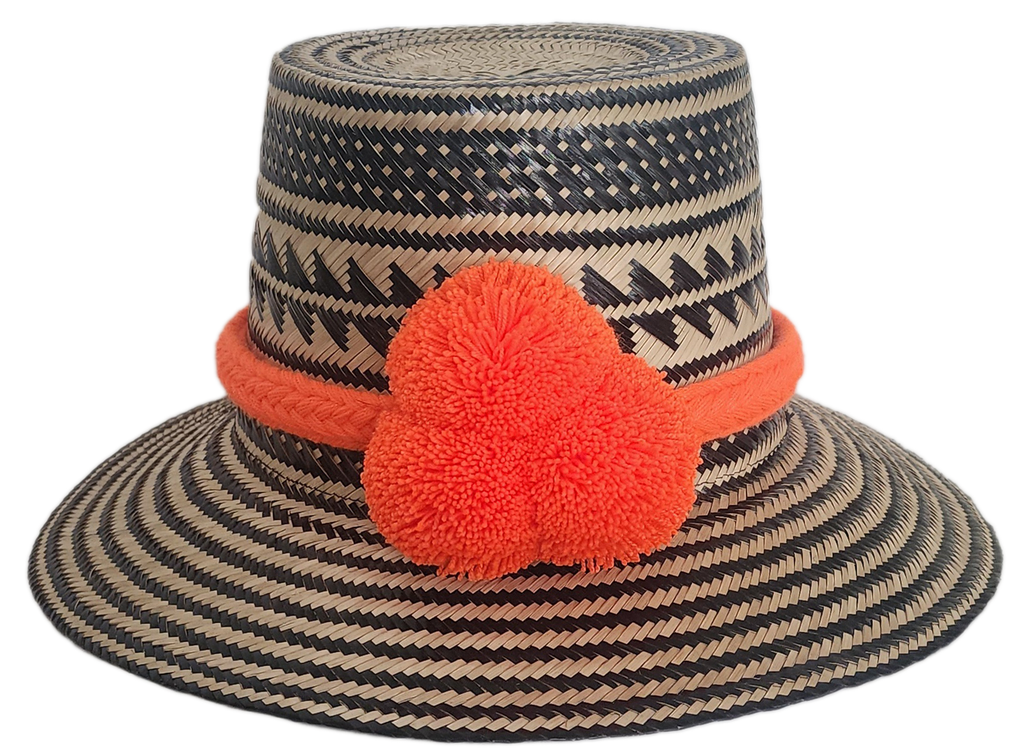 Handwoven Wayuu straw hat with black zigzag tribal patterns and a bold orange pom-pom band. A vibrant artisan boho accessory with modern contrast.