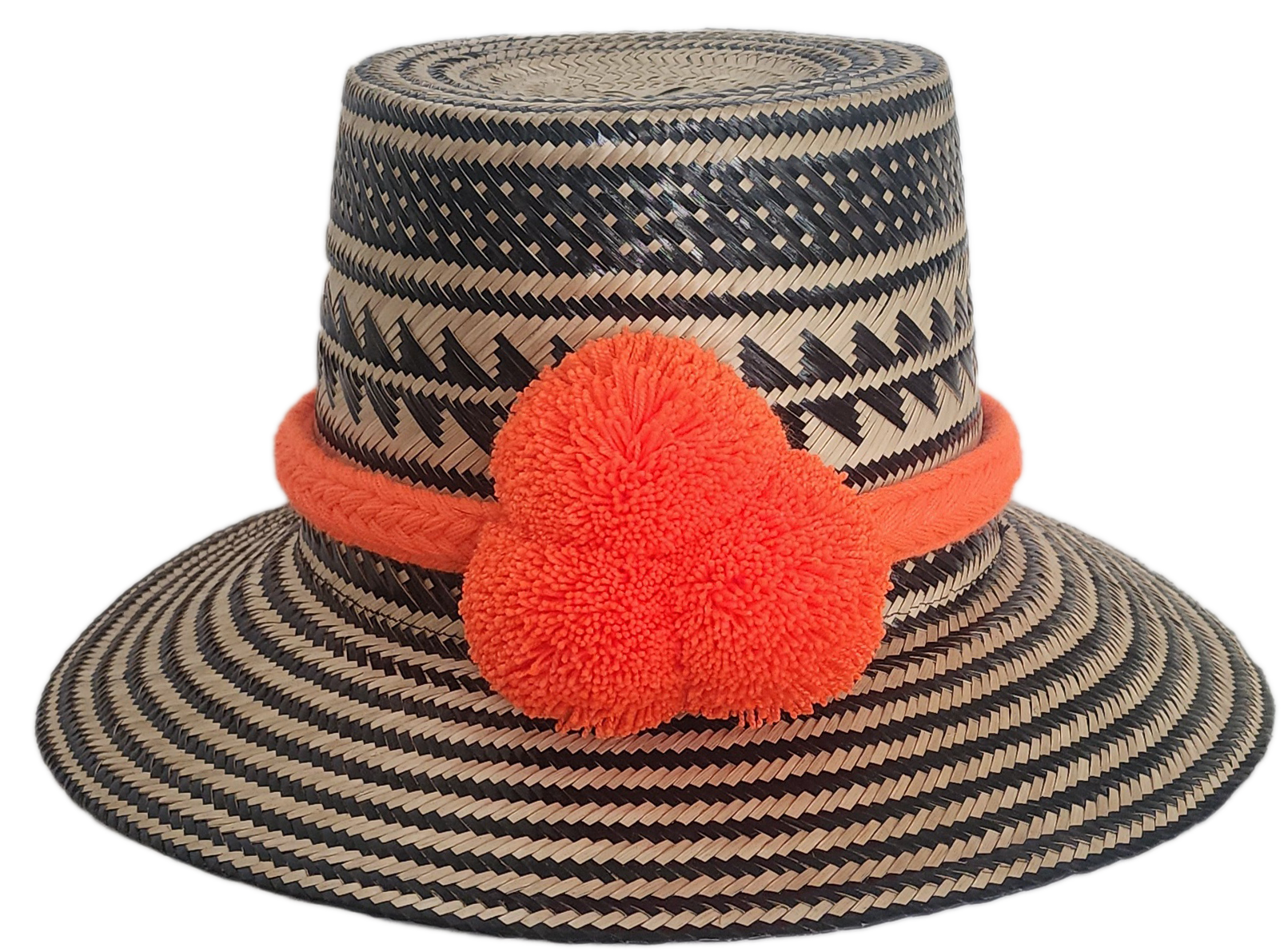 Handwoven Wayuu straw hat with black zigzag tribal patterns and a bold orange pom-pom band. A vibrant artisan boho accessory with modern contrast.
