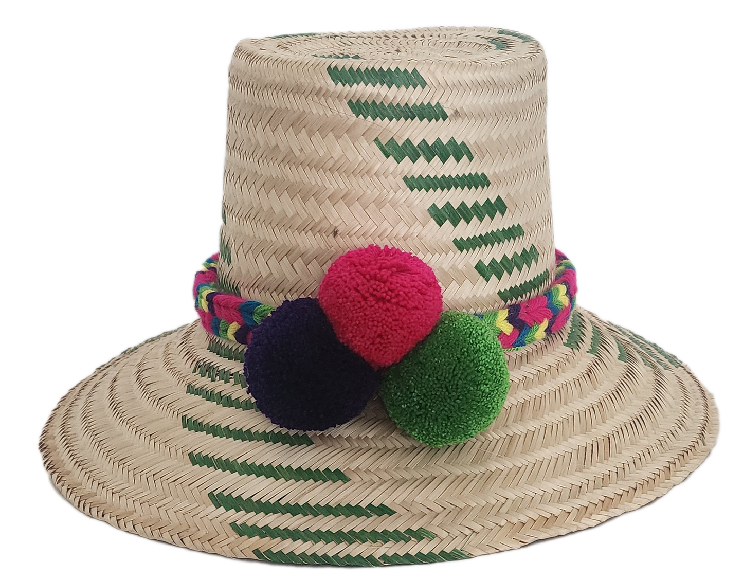 Handwoven Wayuu straw hat with green chevron patterns and a vibrant braided band, finished with red, green, and purple pom-poms. A playful boho accessory.