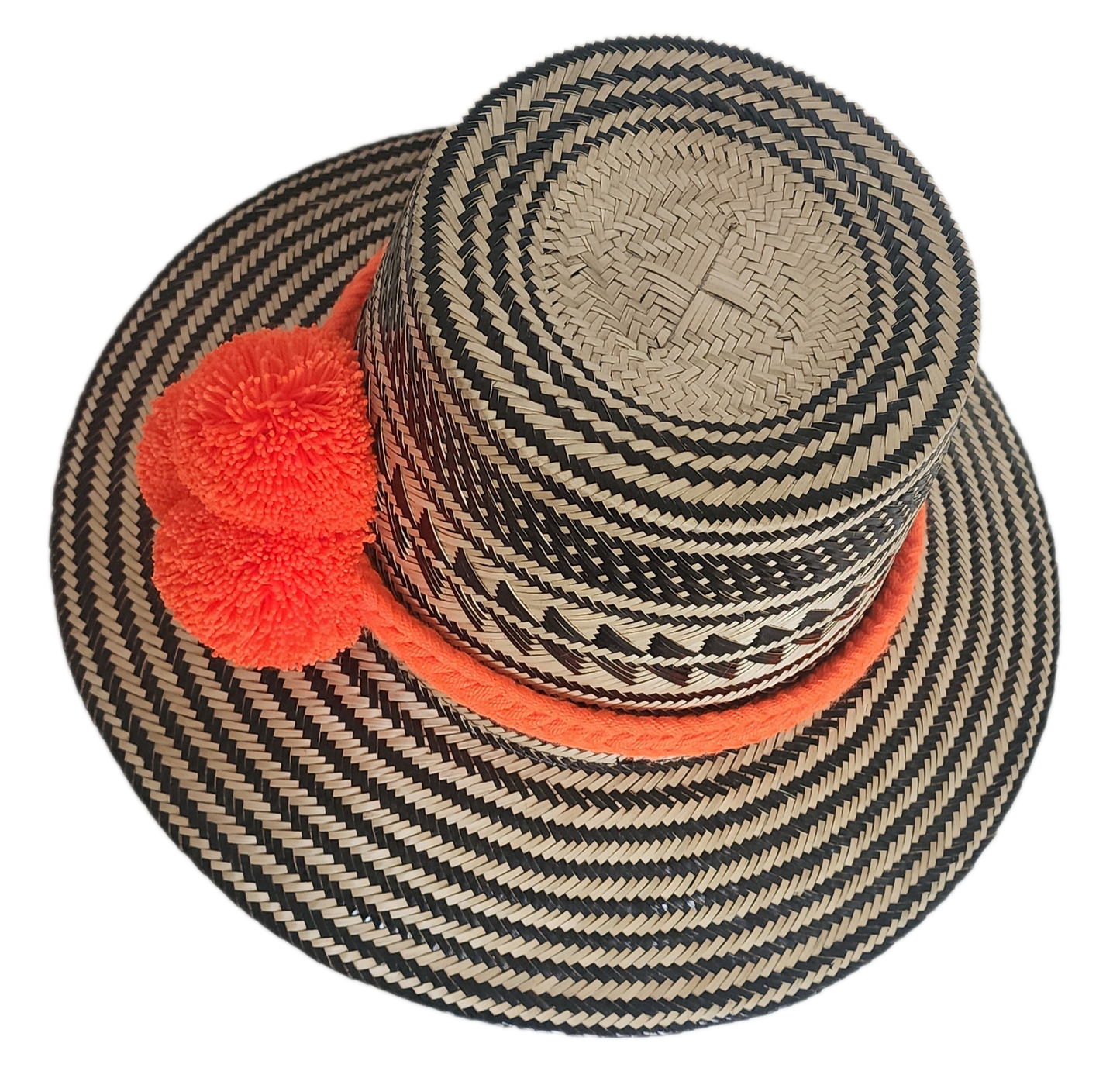 Handwoven Wayuu straw hat with black zigzag tribal patterns and a bold orange pom-pom band. A vibrant artisan boho accessory with modern contrast.