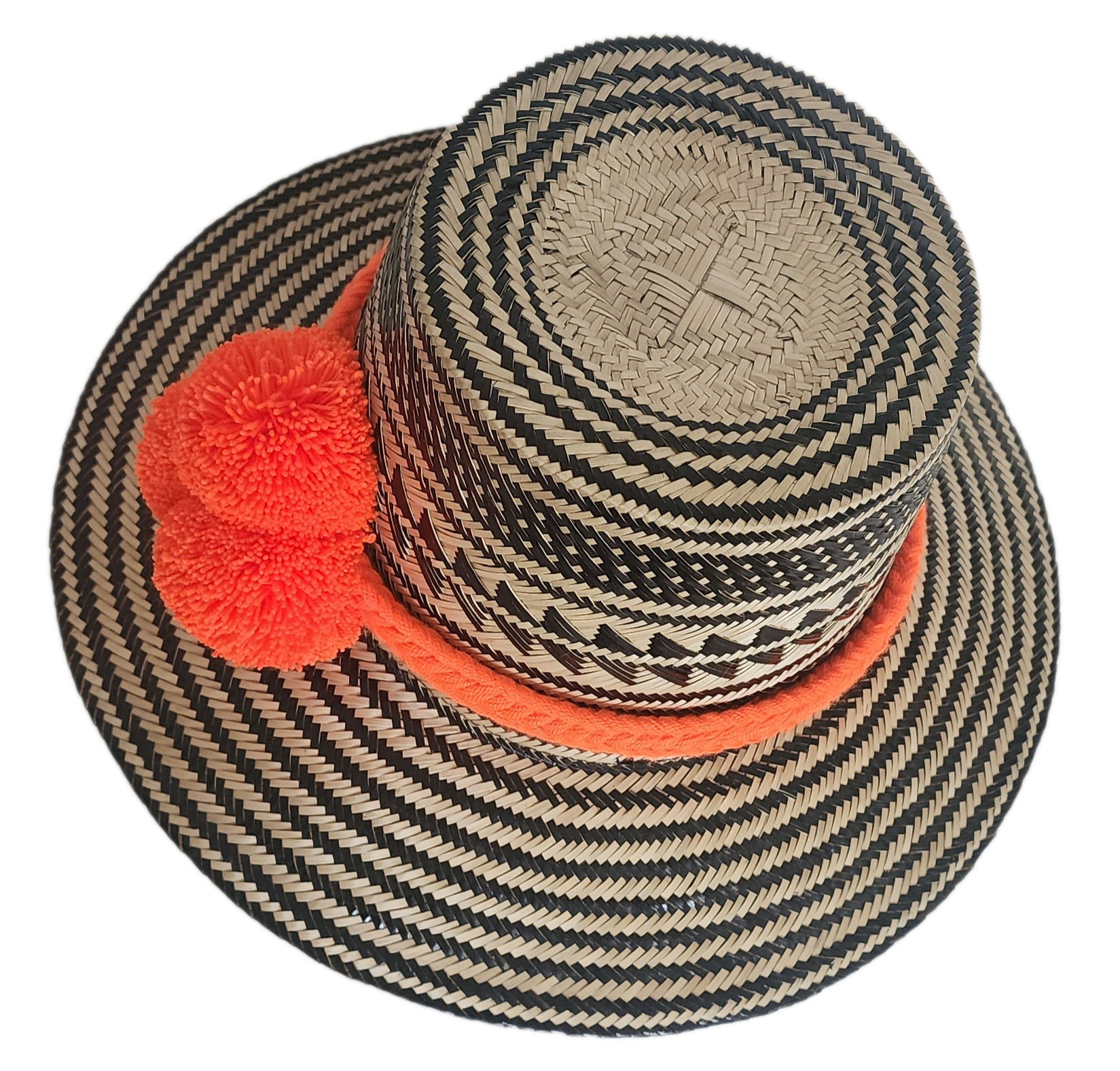 Handwoven Wayuu straw hat with black zigzag tribal patterns and a bold orange pom-pom band. A vibrant artisan boho accessory with modern contrast.