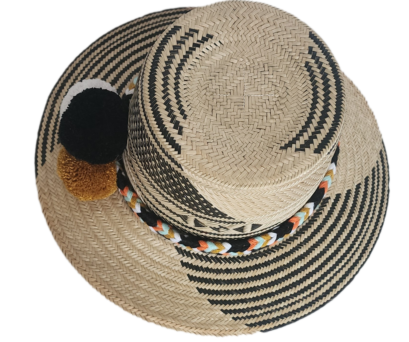 Handwoven Wayuu straw hat with bold black diagonal weave, a colorful braided band, and black, white, and mustard pom-poms. A refined boho fashion piece.