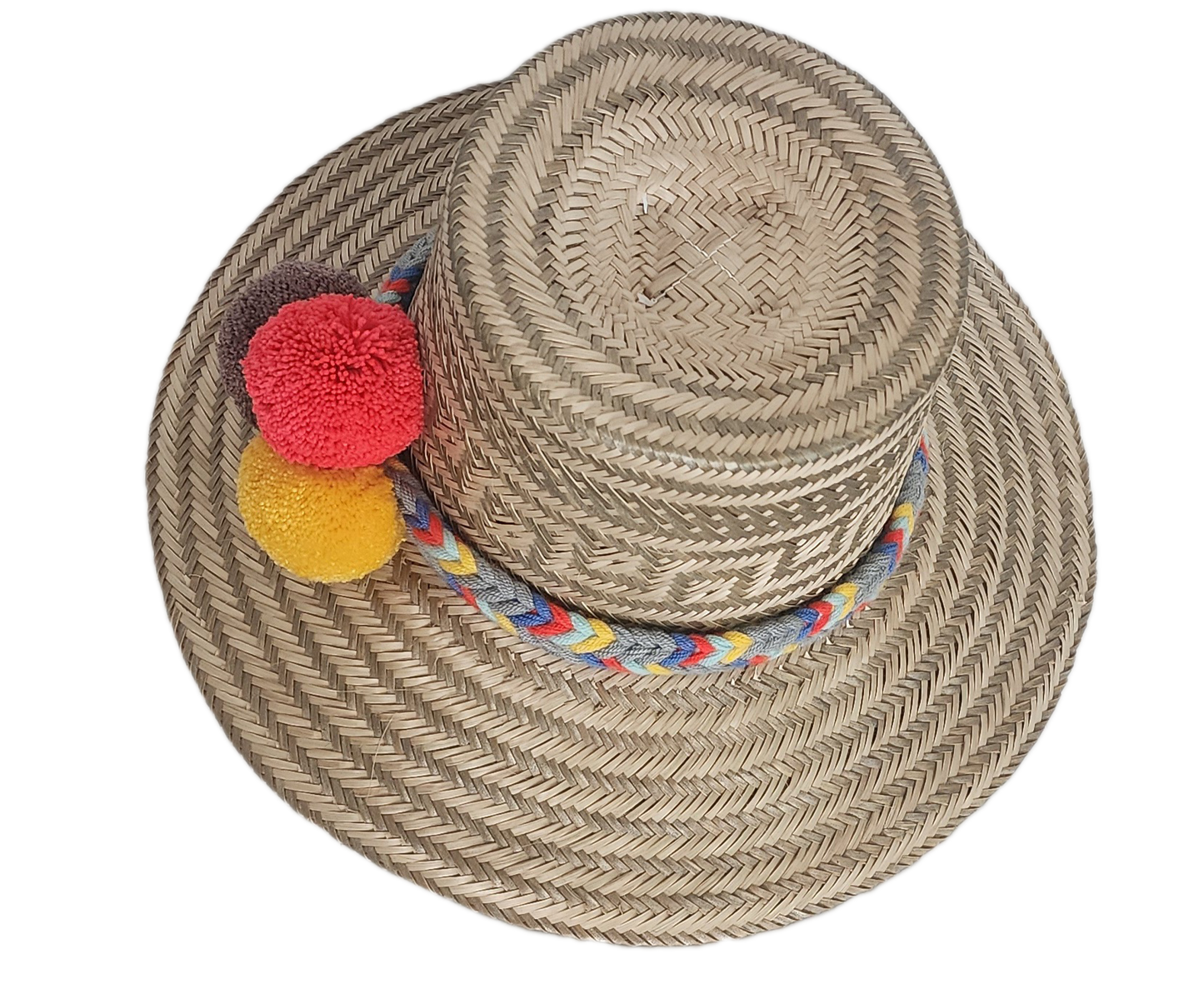 Handwoven Wayuu straw hat with intricate gray-beige tribal patterns, a colorful braided band, and red, yellow, and dark brown pom-poms. Artisan boho style.