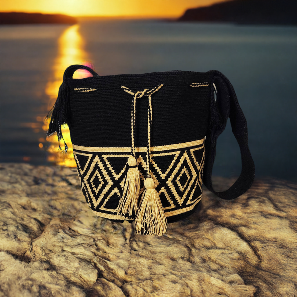 Handmade Wayuu crochet bag in black and beige, featuring geometric diamond patterns and oversized beige tassels, artisan-crafted crossbody.
