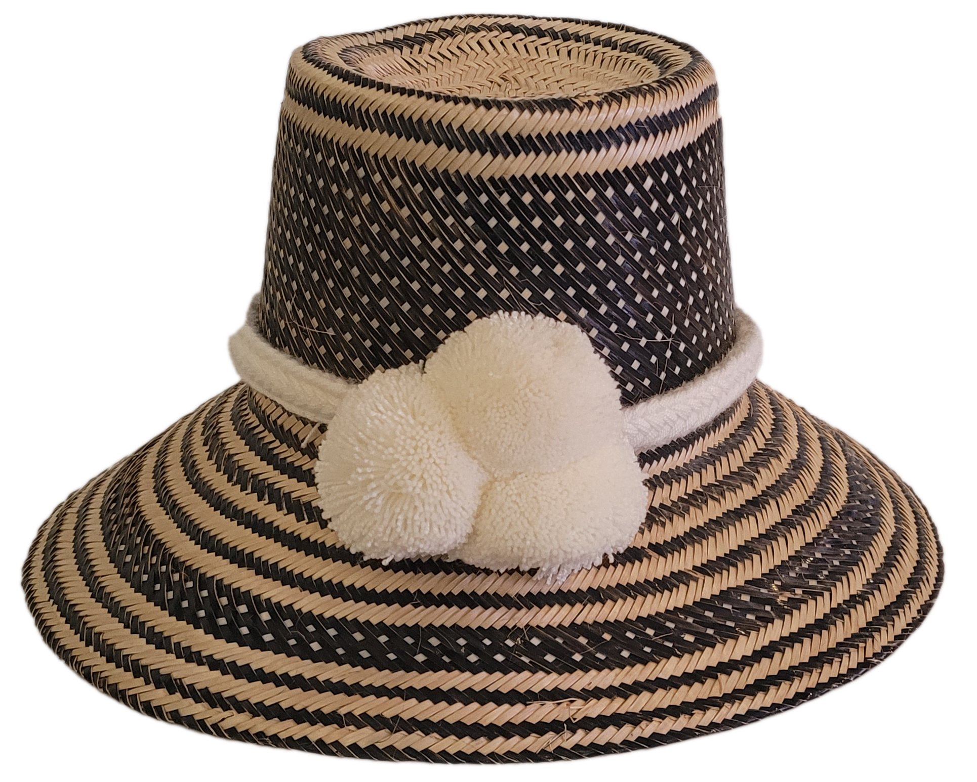 Boho handmade Wayuu hat in black and natural tones with ivory white pompoms and woven geometric patterns — artisan-crafted straw hat for women.