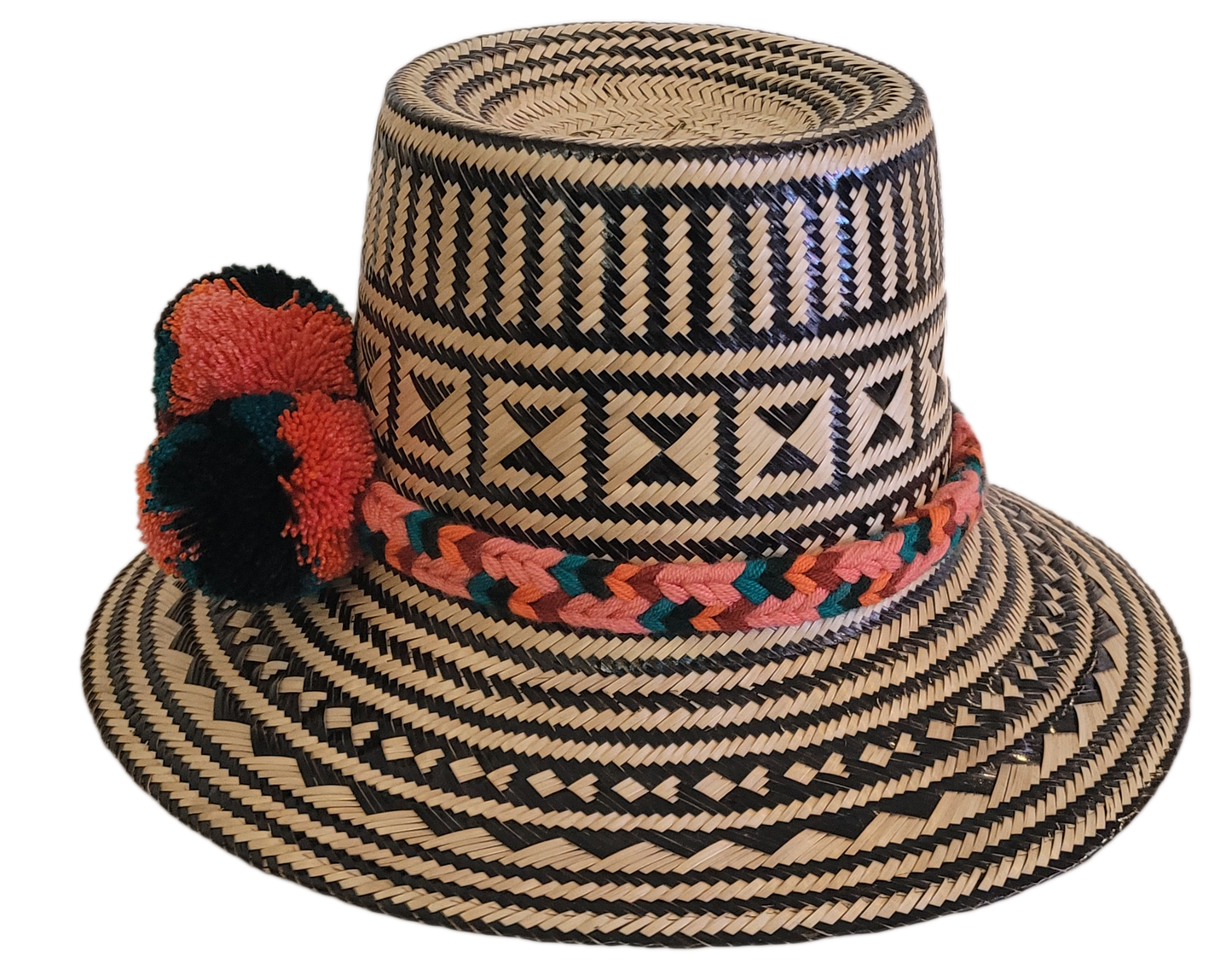 Bohemian-style handmade Wayuu hat featuring intricate black designs and multicolor pompoms in coral, green, and burgundy — crafted from Iraca palm.