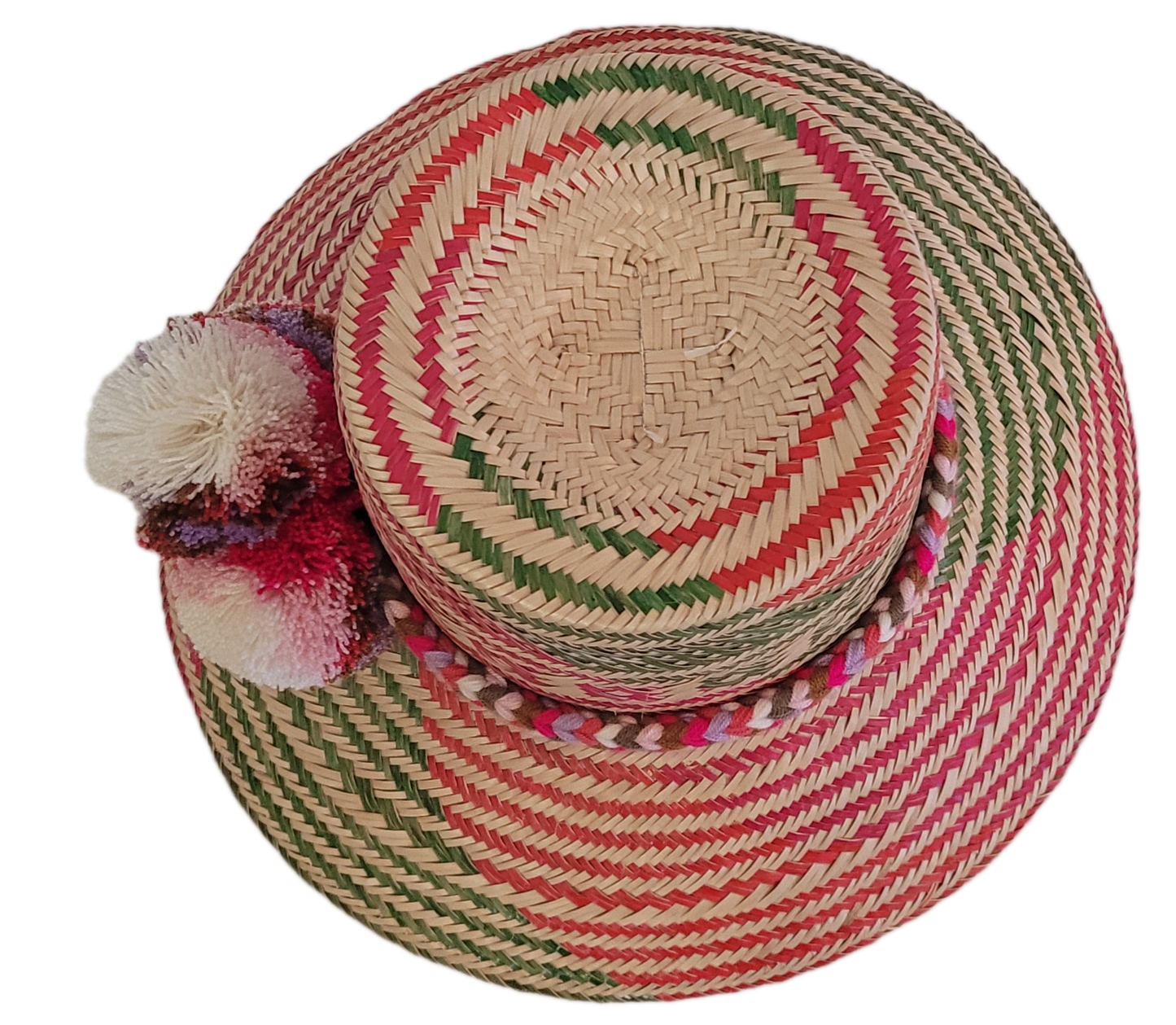 Artisan Wayuu straw hat with bold zigzag patterns and fluffy bohemian pom-poms in white, pink, and burgundy — lightweight and handmade fashion.