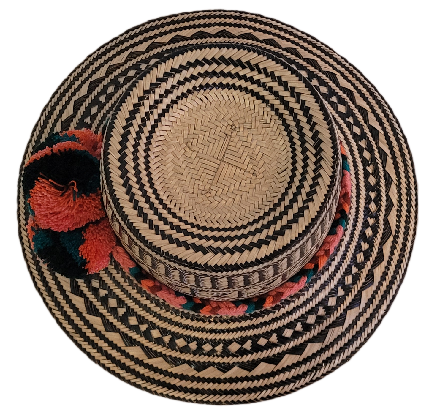 Striking black and tan Wayuu straw hat with bold tribal patterns and braided band, finished with handmade coral and green pompoms — artisan boho accessory.