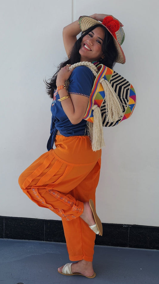 A woman carrying a bohemian purse and a colorful boho hat