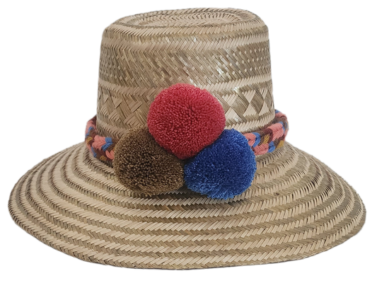 Handwoven Wayuu straw hat with colorful braided band and red, brown, and blue pom-poms — a boho, artisanal summer accessory.