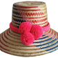 "Colorful handmade Wayuu hat from Iraca palm fibers, adorned with culturally significant pompoms, showcasing unique weaving b