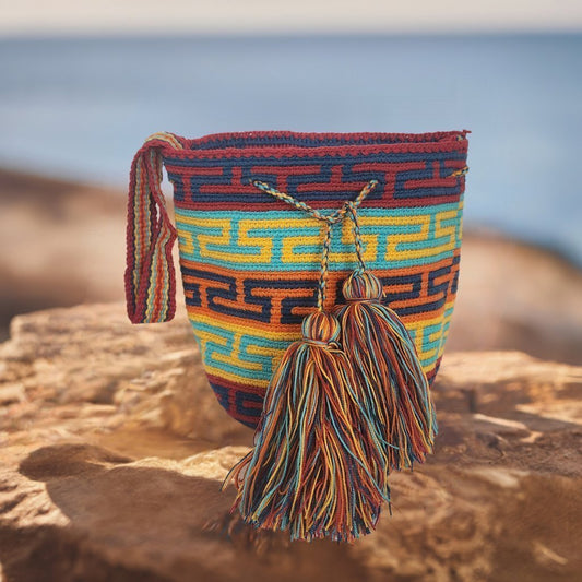 Image ALT text: "Colorful handmade crochet Wayuu bag showcasing boho and bohemian styles, crafted by Wayuu artisans from Colombia and Venezuela. Features vibrant, intricate crochet patterns typical of the Guajira Peninsula, adjustable handwoven straps, and designed for both style and functionality. Perfect for a beach day or adding a splash of color to everyday wear, supporting Fair Trade and Wayuu Taya Foundation."