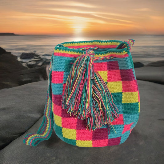 Image of a colorful, handmade crochet Wayuu bag featuring intricate bohemian patterns. This boho crossbody bag, created by indigenous Wayuu artisans from Colombia and Venezuela, showcases vibrant colors and geometric motifs inspired by the Guajira Peninsula. The bag varies in size and includes adjustable straps, making it both stylish and functional for everyday use or beach outings.