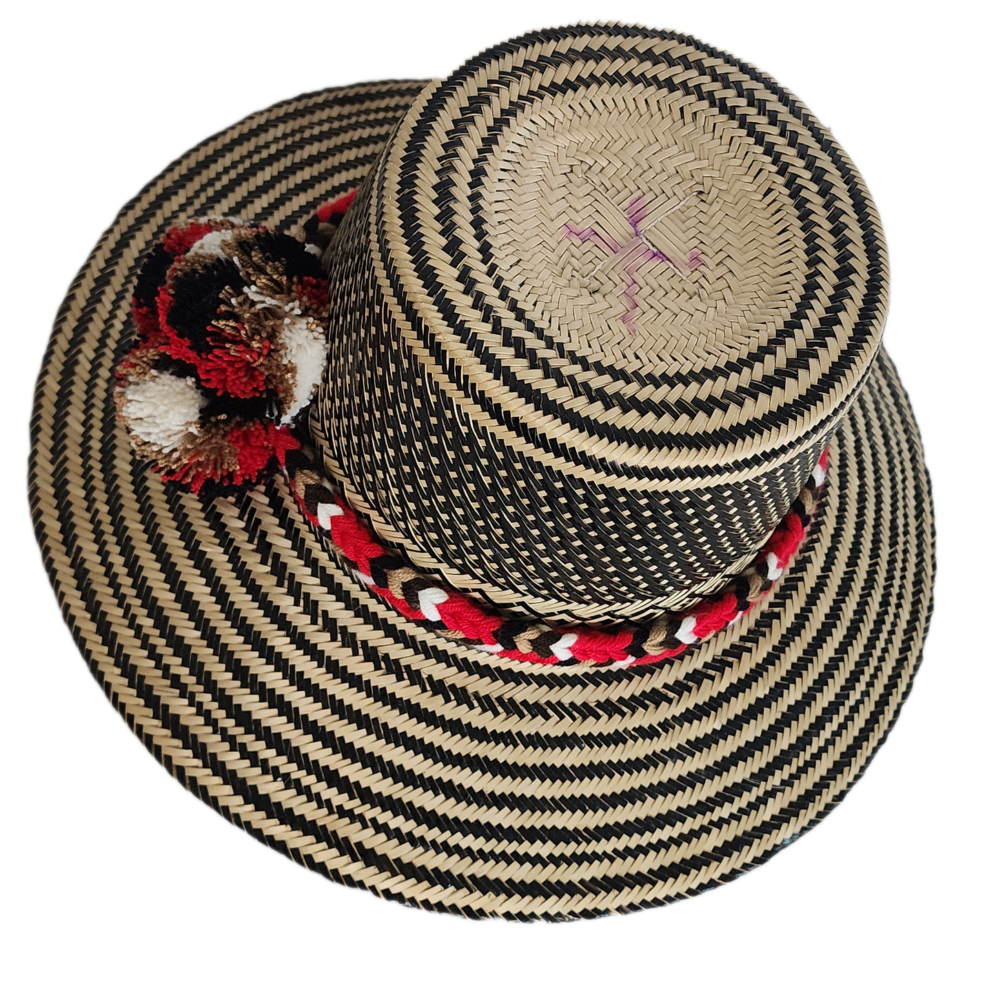 Colorful boho straw hat handwoven by Wayuu artisans, featuring a black and natural pattern, red-and-white braided band, and vibrant pom-poms — a bohemian fashion accessory perfect for summer.