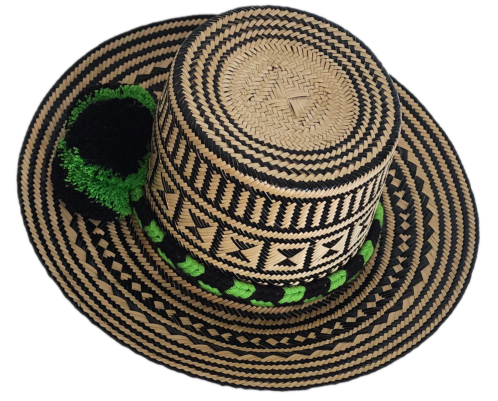 Handcrafted Wayuu straw hat with bold black geometric patterns, natural beige base, a wide circular brim, and a black and green pom-pom band accent.