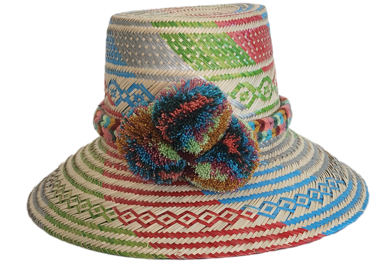 A vibrant, handmade straw hat featuring a patchwork of colorful geometric patterns in red, green, blue, and grey, and a multicolored pompom band with orange, blue, and red.