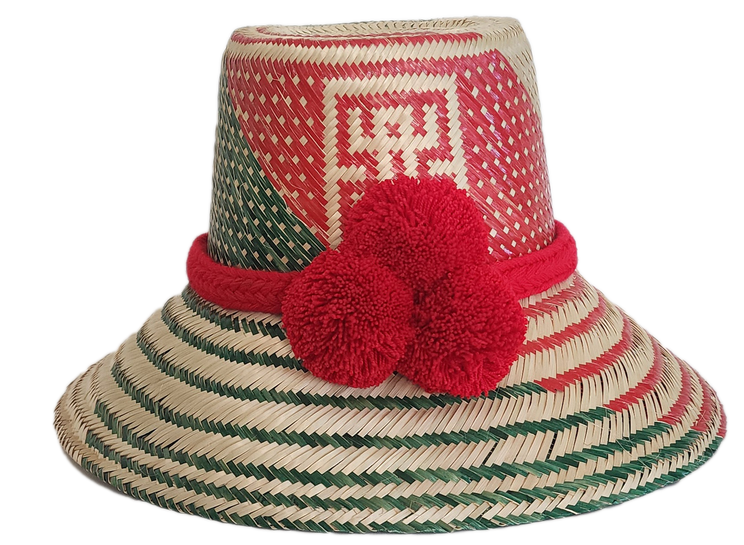 A vibrant, bohemian  handmade straw hat featuring red and green geometric patterns and a bold red pompom band with three fluffy pompoms.