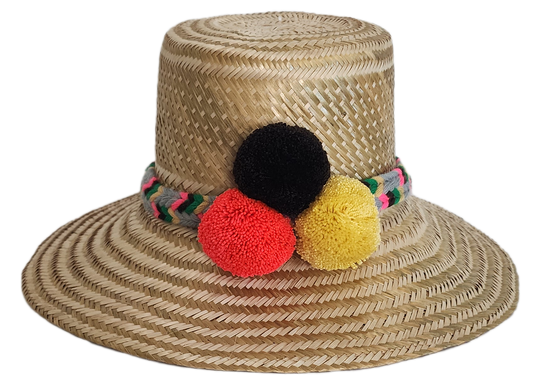 Boho Wayuu straw hat with natural weave, colorful braided band, and vibrant pom-poms in black, red, and yellow — a handcrafted, bohemian summer accessory full of artisan charm.