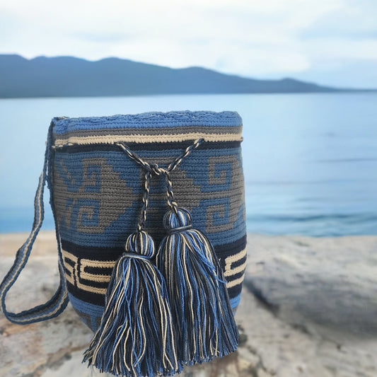 A vibrant and colorful crochet bag featuring boho-inspired Wayuu patterns. The bohemian-style accessory is intricately handcrafted with a multitude of bright, vivid colors, showcasing traditional Wayuu designs in a stylish, modern crochet technique.