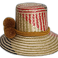 Natural palm Wayuu hat featuring olive, red, and black pattern with yellow trim.Bohemian Wayuu straw hat in muted red, green, and yellow tones with pompoms


