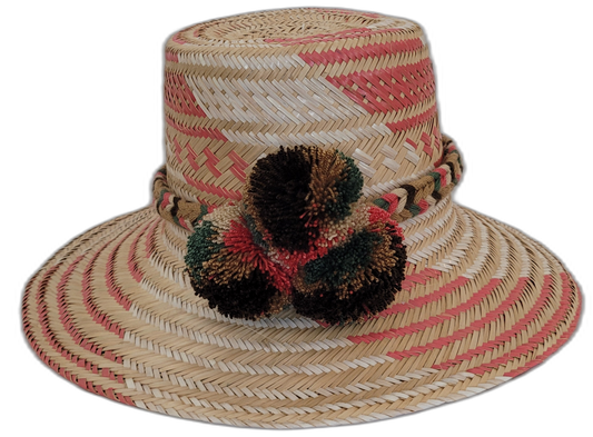Handmade Wayuu straw hat with red, brown, and green pompoms.Bohemian Wayuu hat featuring soft tones and textured pompoms

