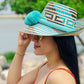 "Artisan-crafted Wayuu hat woven from Iraca palm fibers, adjustable, with vibrant pompoms symbolizing prosperity."