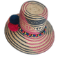 Artisan-crafted hat with multicolor pompom cluster and geometric navy-pink weave.