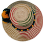 Wayuu woven straw hat with red patterns and vibrant pompoms
