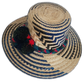Dark-toned Wayuu straw hat with green, red, and black pompoms and braided band.