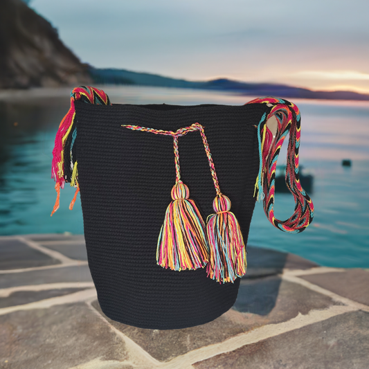 Black handmade Wayuu crochet bag with vibrant multicolor tassels and woven strap. A boho chick bag crafted by Wayuu artisans in Colombia.