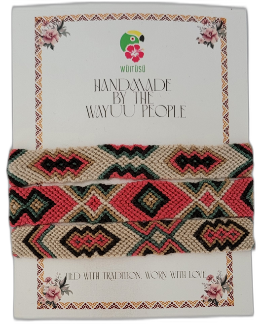 Bohemian handmade Wayuu friendship bracelet with bold tribal patterns in cream, coral, green, and black — a chic artisan piece with symbolic meaning.

